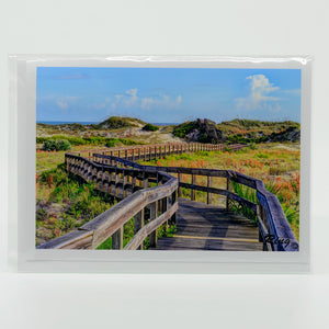 A boardwalk to the beach on a glossy greeting card