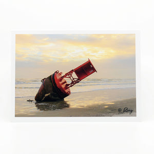 A large red buoy on the beach on a 5"x7" glossy greeting card