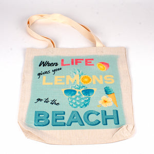 A polyester linen tote bag with words When life gives you lemons go to the beach